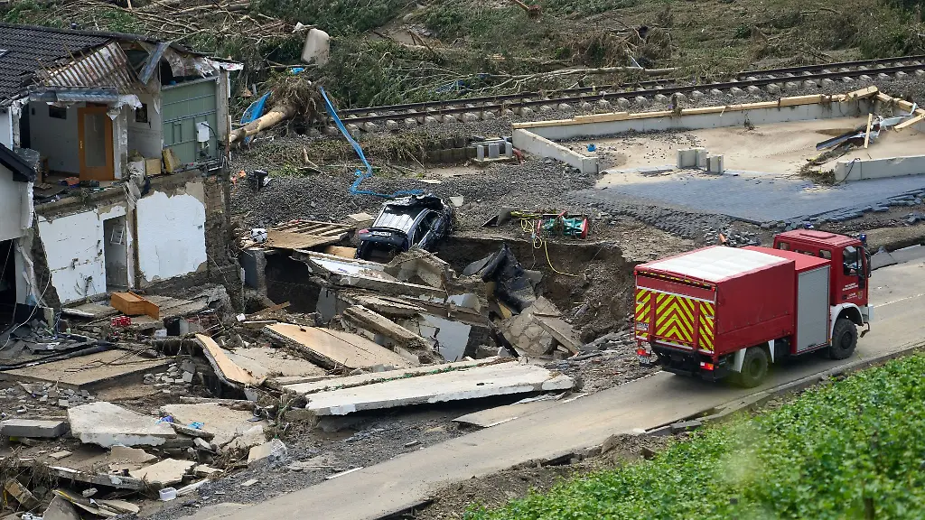 Ein-Einsatzfahrzeug-der-Feuerwehr-steht-im-Ahrtal-im-Ortsteil-Walporzheim-vor-zerstoerten-Haeusern
