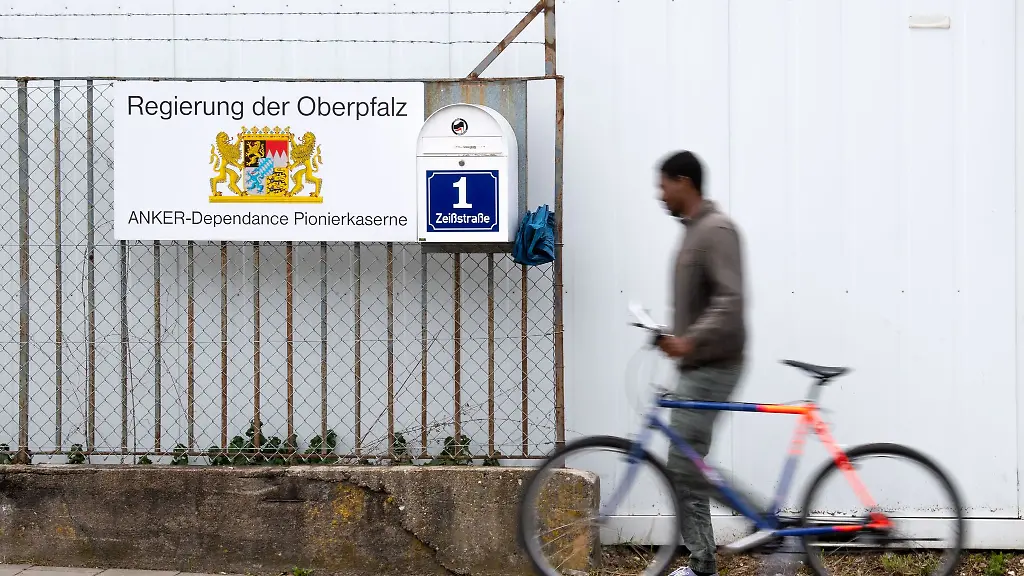Ein-Mann-mit-einem-Fahrrad-geht-an-einem-Hinweisschild-vom-Ankerzentrum-in-der-Zeissstrasse-vorbei