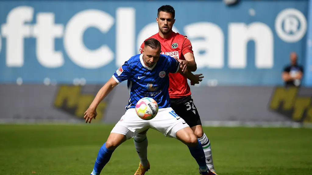 Rostocks-Ryan-Malone-l-und-Hannovers-Luka-Krajnc-kaempfen-um-den-Ball