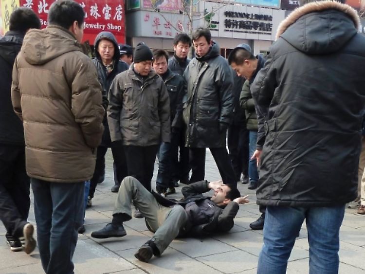 Zwischenfall in der Pekinger Fußgängerzone Wangfujing: Nicht identifizierte Männer in zivil umringen aus Sicherheitsgründen einen ausländischen Journalisten - nachdem sie ihn zu Boden gestoßen haben.