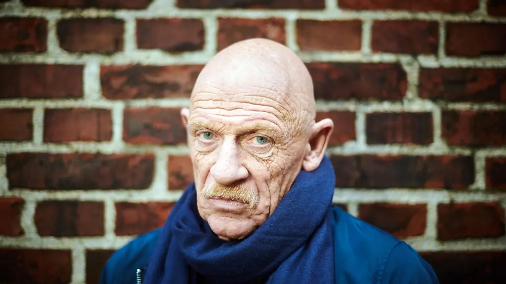 Der-Schauspieler-und-ehemalige-Gefaengnisarzt-Joe-Bausch-steht-vor-einer-Mauer-der-JVA-Werl