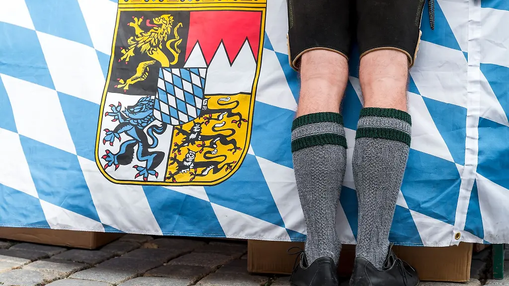 Ein-Mann-in-Tracht-steht-vor-der-bayerischen-Landesfahne-auf-dem-Gredinger-Trachtenmarkt