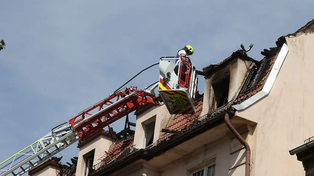 Feuerwehrleute-und-Statiker-untersuchen-das-Dach-des-Mehrfamilienhauses