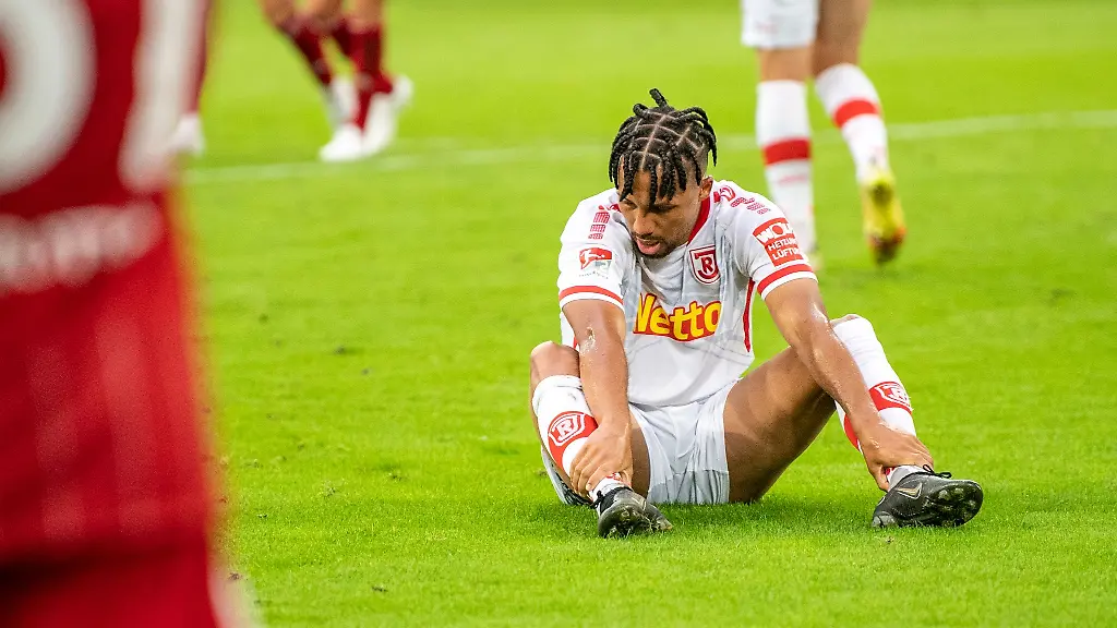 Regensburgs-Leon-Guwara-sitzt-nach-dem-Tor-zum-1-0-auf-dem-Rasen