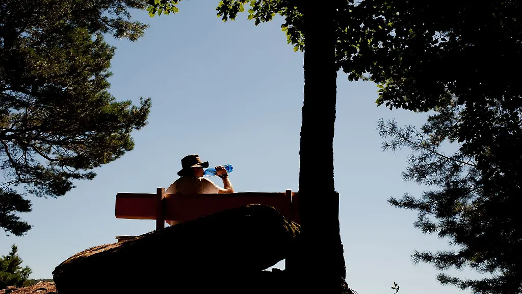 Ein-Wanderer-trinkt-auf-einer-Bank-bei-Lug-aus-einer-Flasche