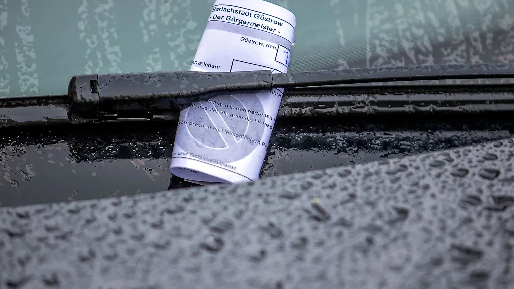 Ein-Knoellchen-steckt-bei-Regen-unter-dem-Scheibenwischer-eines-Autos-das-falsch-geparkt-wurde