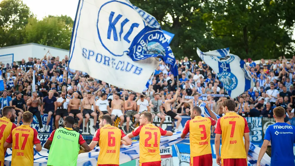 Die-Spieler-des-Karlsruher-SC-feiern-nach-dem-Sieg-gemeinsam-mit-ihren-Fans-vor-dem-Gaesteblock
