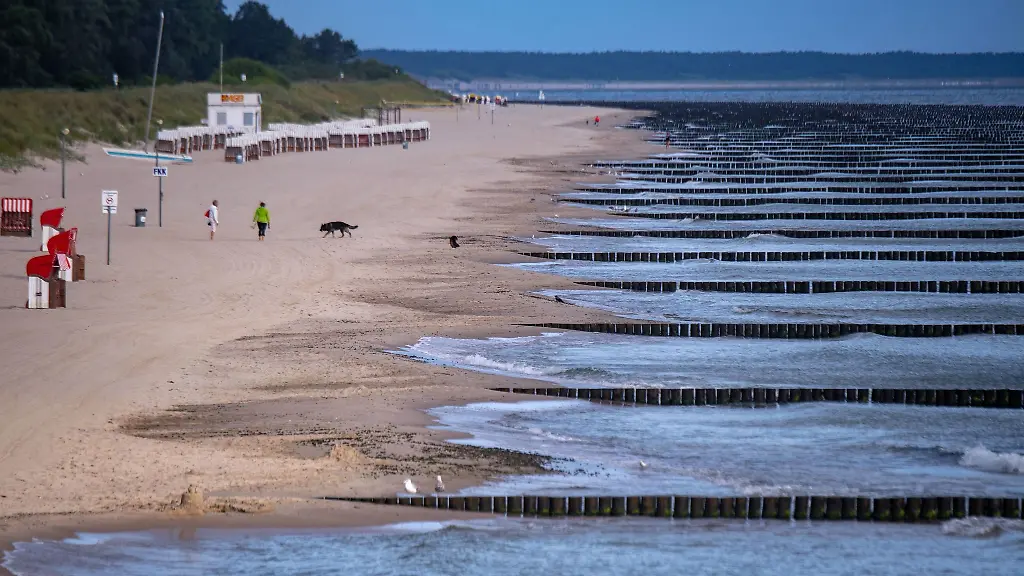 Spaziergaengerinnen-sind-am-Strand-in-der-Naehe-der-Seebruecke-unterwegs