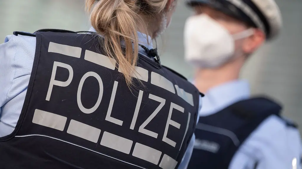 Eine-Polizistin-und-ein-Polizist-mit-FFP2-Maske-stehen-sich-gegenueber
