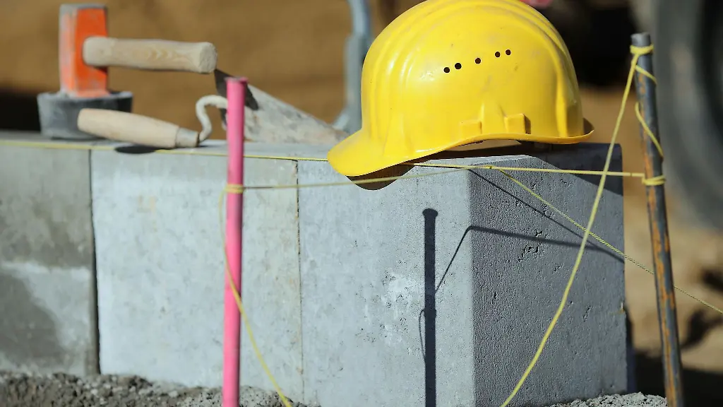 Ein-Bauarbeiterhelm-liegt-auf-einer-Baustelle-auf-Mauerwerk