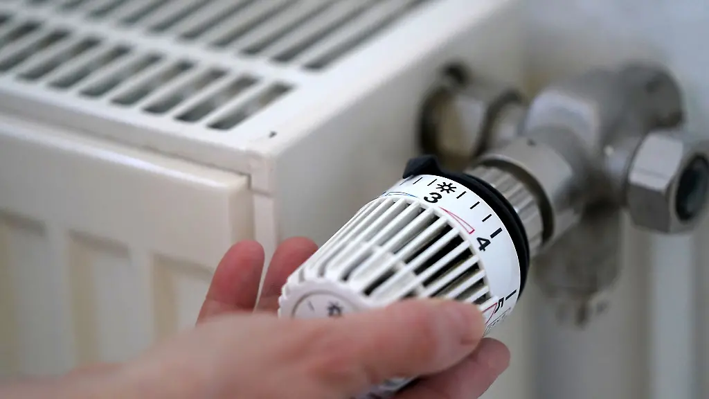 Eine-Frau-dreht-an-einem-Heizungsthermostat