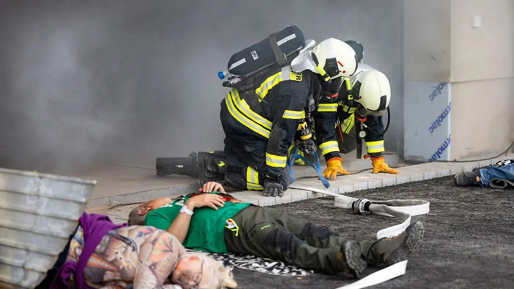 Feuerwehrleute-kriechen-bei-einer-Grossuebung-aus-einem-Gefahrenbereich