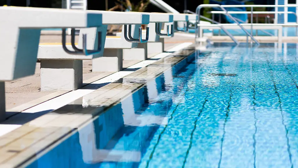 Absprungbloecke-stehen-in-einem-Freibad-am-Rand-des-leeren-Beckens