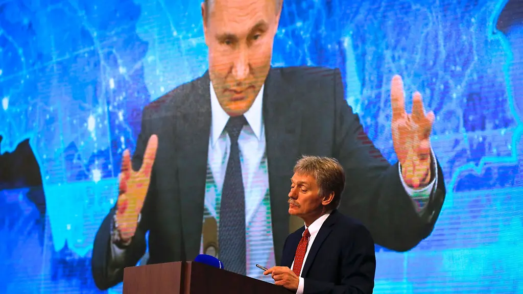 Russlands-Praesident-Wladimir-Putin-ist-auf-einem-Bildschirm-zu-sehen-im-Vordergrund-steht-sein-Sprecher-Dmitri-Peskow-Archivbild-Beide-heben-das-grosse-militaerische-Potenzial-Moskaus-hervor
