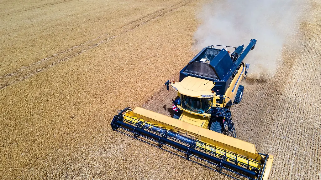 Ein-Landwirt-erntet-mit-seinem-Maehdrescher-Gerste-auf-einem-Feld