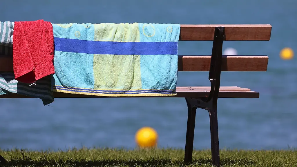 Handtuecher-haengen-am-Ufer-des-Strandbades-zum-Trocknen-ueber-einer-Bank