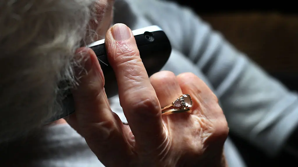 Eine-Rentnerin-haelt-ein-Telefon-in-der-Hand