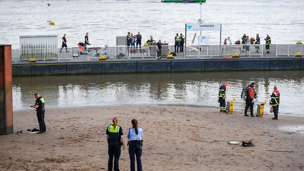 Einsatzkraefte-stehen-auf-dem-Anleger-Teufelsbrueck-und-am-Ufer-der-Elbe