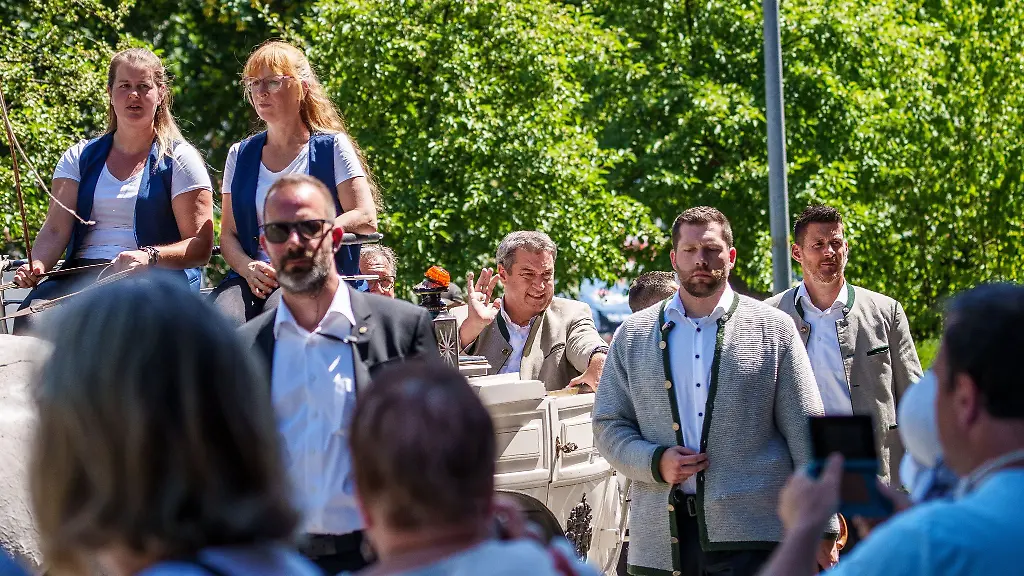 Markus-Soeder-faehrt-umgeben-von-viel-Sicherheitspersonal-auf-dem-Festumzug-in-einer-Kutsche-mit