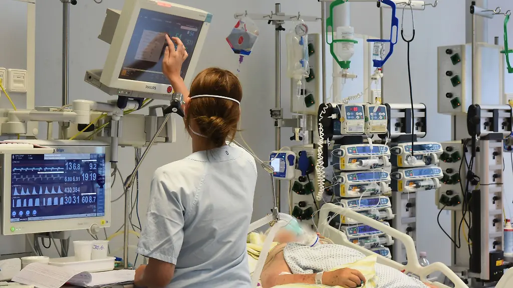 Auf-einer-Station-im-Klinikum-St-Georg-steht-eine-Mitarbeiterin-am-Bett-einer-Patientin