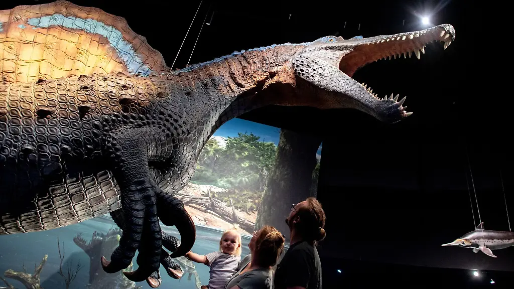 Eine-Familie-betrachtet-ein-lebensgrosses-Modell-eines-Spinosaurus-in-der-neuen-Erlebnisausstellung-Saurier-Giganten-der-Meere