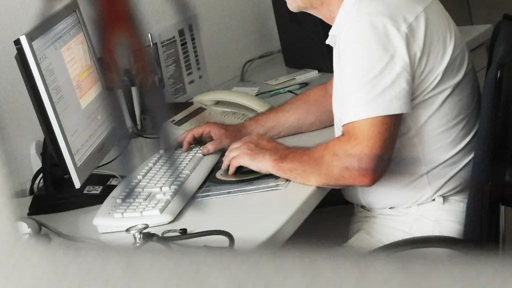Ein-Arzt-sitzt-in-seiner-Praxis-an-einem-Computer