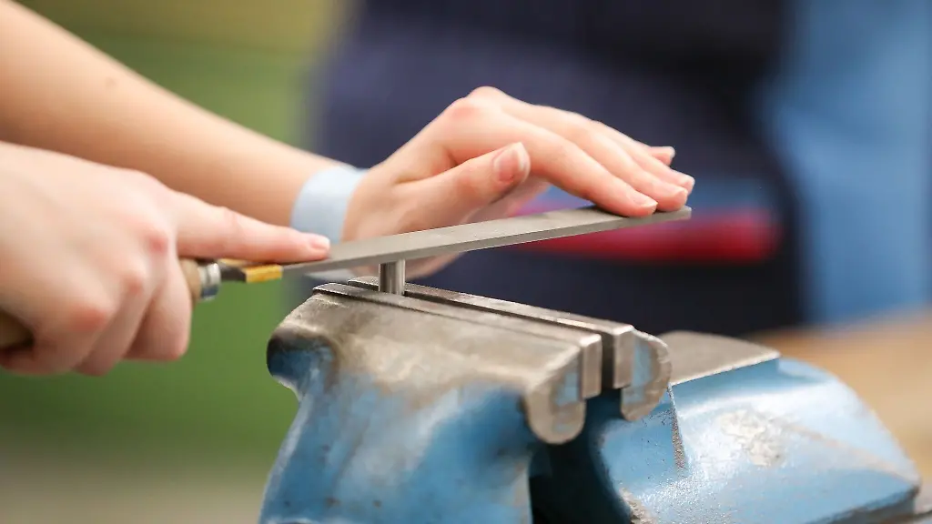 Eine-Auszubildende-feilt-an-einem-Werkstueck