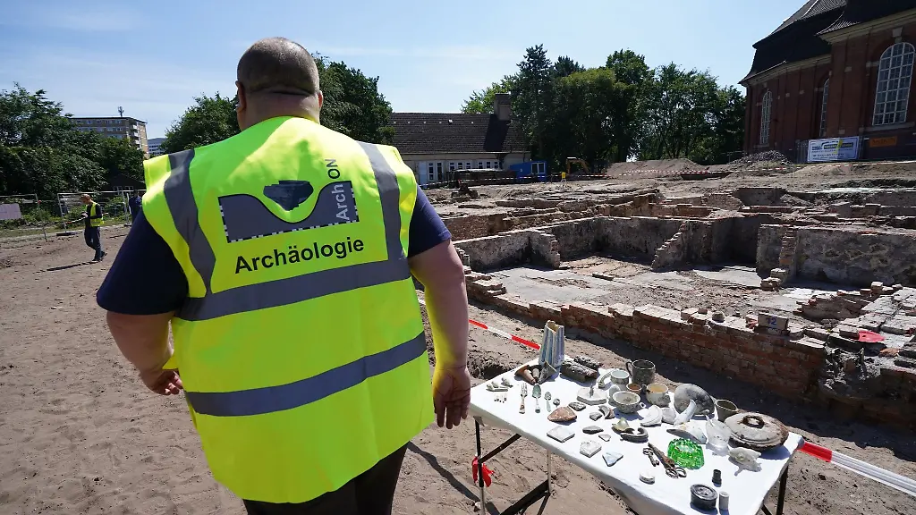 Ein-Mitarbeiter-der-Grabungsfirma-ArchOn-geht-an-Fundstuecken-am-Grabungsareal-rund-um-die-Hauptkirche-St-Trinitatis-in-Altona-vorbei