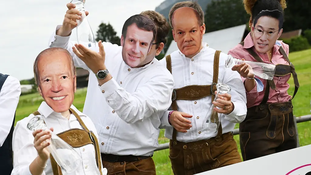 Demonstranten-stehen-in-Tracht-mit-Politiker-Masken-auf-einer-Wiese-und-halten-leere-Weissbierglaeser-hoch