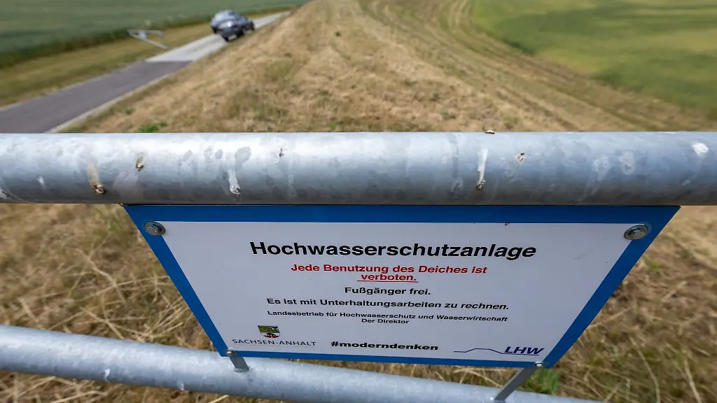 Ein-Schild-informiert-ueber-den-Zugang-zu-einem-Deich-bei-Retzau-an-der-Mulde-Der-Hochwasserschutz-im-Landkreis-Anhalt-Bitterfeld-kommt-weiter-voran