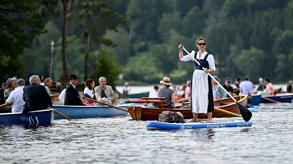 Ein-Frau-im-Dirndl-nimmt-auf-einem-Stand-Up-Board-an-der-Seeprozession-zu-Fronleichnam-auf-dem-Staffelsee-teil
