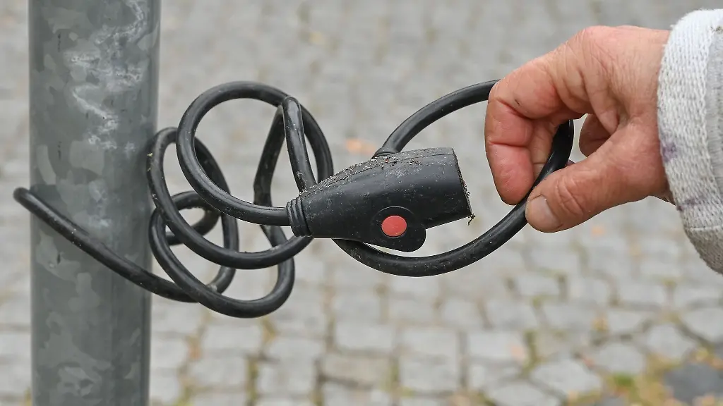 Eine-Fraz-zeigt-ein-Fahrradschloss-angeschlossen-an-einem-Mast