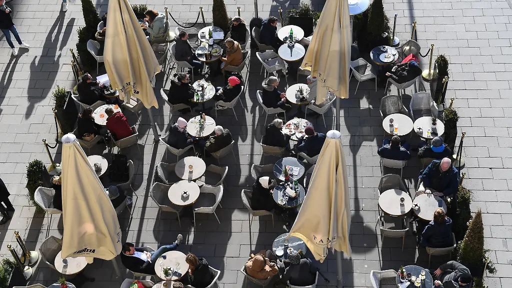 Gaeste-sitzen-vor-einem-Cafe-in-der-Sonne