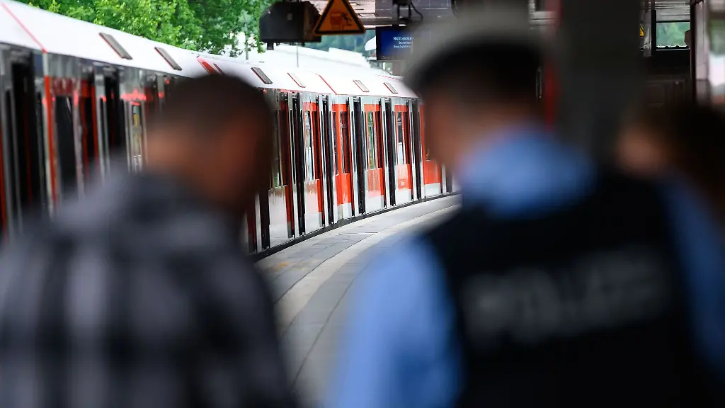 Ermittler-und-ein-Bundespolizist-stehen-am-Bahnsteig-vor-einer-S-Bahn