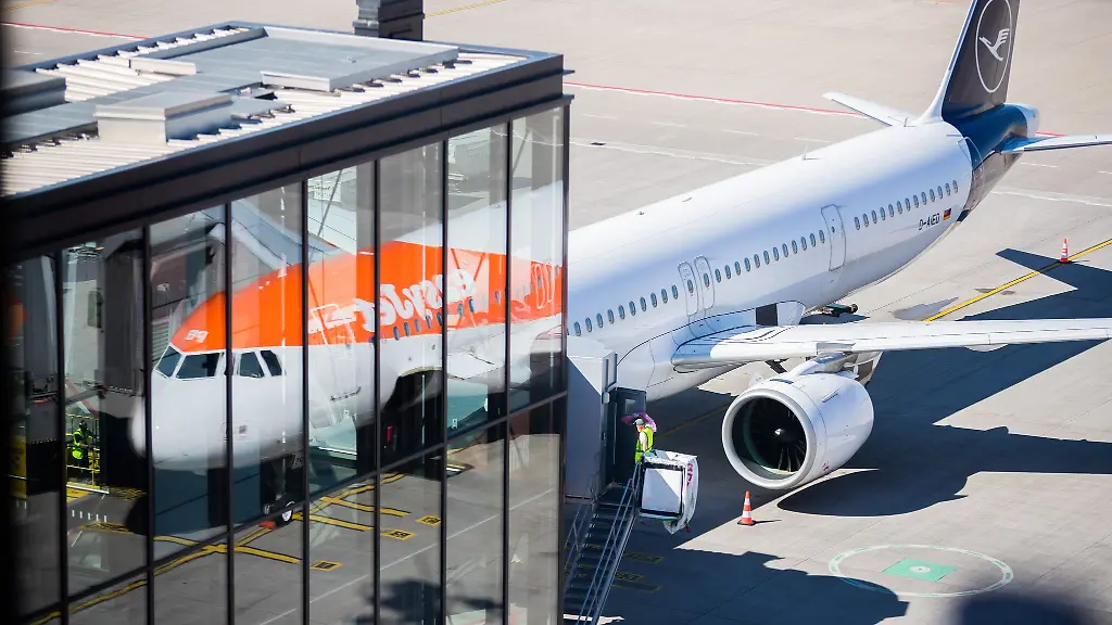 Ein-Flugzeug-von-easyJet-spiegelt-sich-neben-einer-Maschine-der-Lufthansa-in-einer-Glasfassade