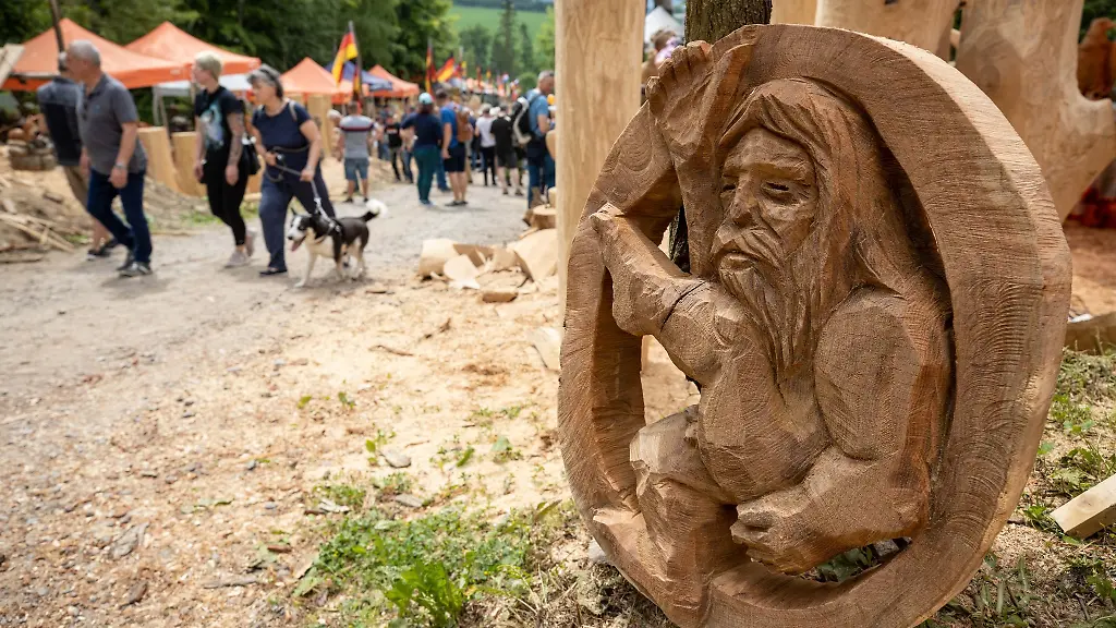 Ein-sitzendes-Holzmaennchen-in-einem-Baumstamm-steht-auf-dem-Boden-beim-19-Blockhausencup