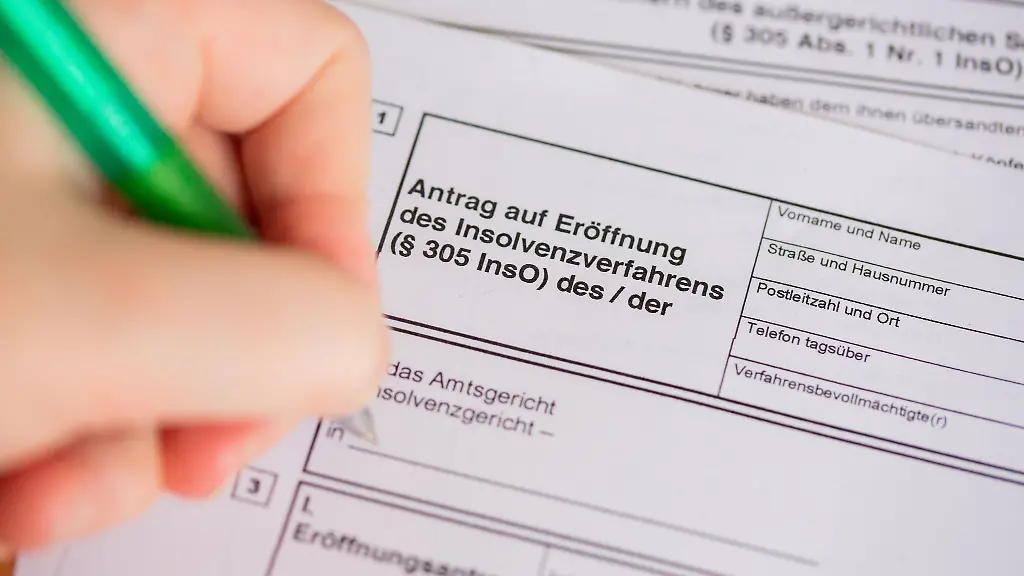 Eine-Person-fuellt-einen-Antrag-zur-Eroeffnung-eines-Insolvenzverfahrens-aus