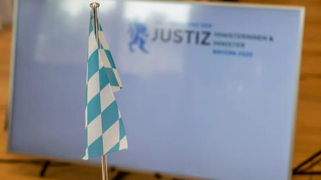 Die-bayerische-Landesflagge-steht-bei-der-Justizministerkonferenz-vor-einem-Bildschirm