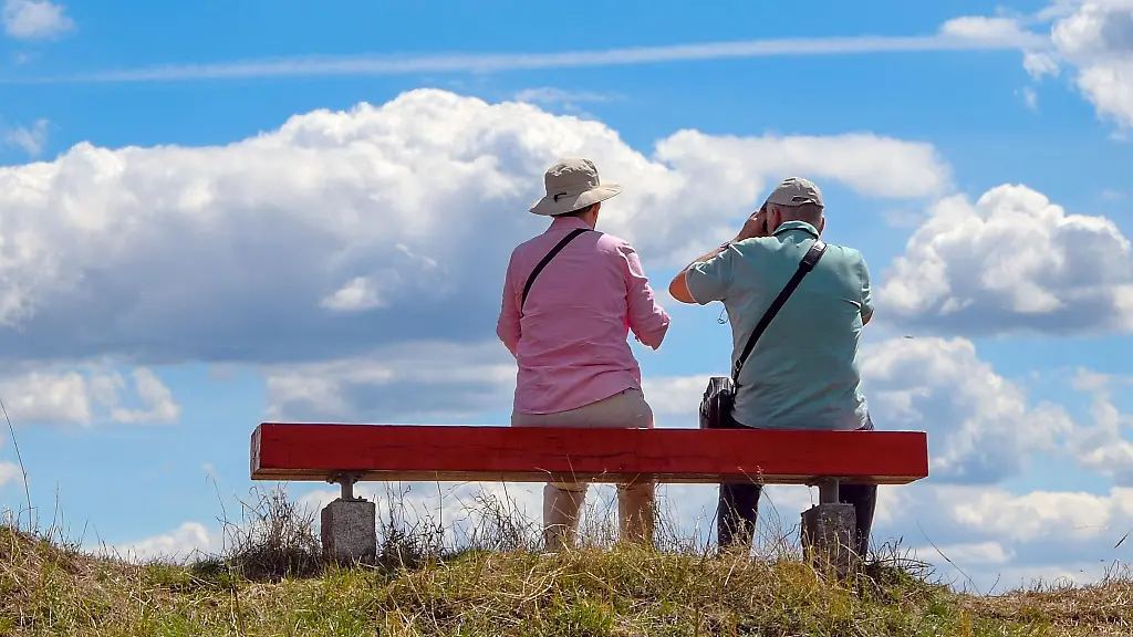 Ein-Mann-und-eine-Frau-sitzen-bei-strahlendem-Sonnenschein-auf-einer-Bank
