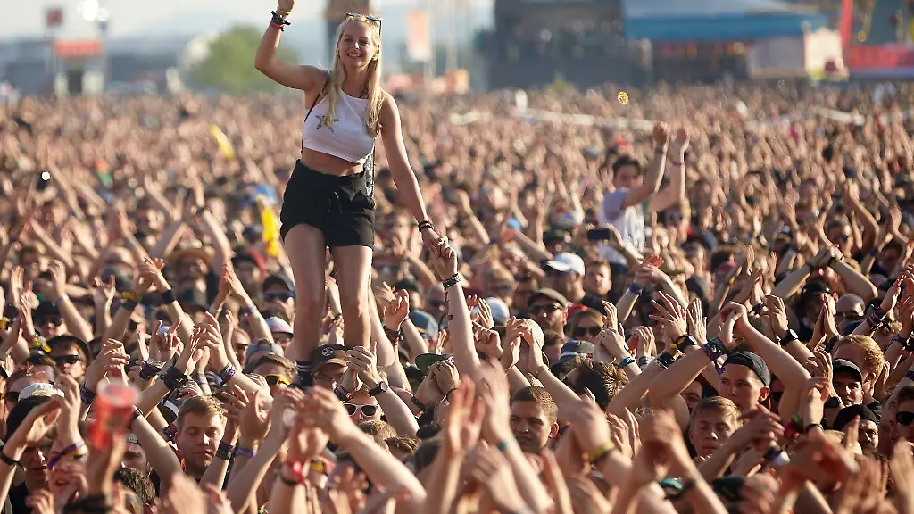Eine-Frau-steht-bei-einem-Auftritt-auf-dem-Musikfestival-Rock-am-Ring-auf-den-Schultern-eines-Zuschauers