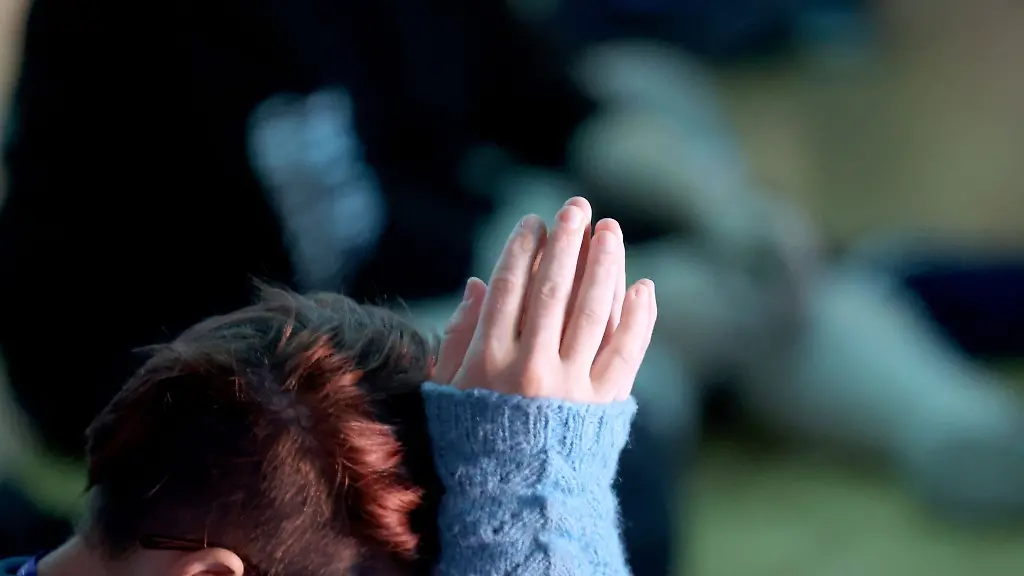 Eine-Teilnehmerin-haelt-beim-Abschlussgottesdienst-in-der-Messehalle-die-Haende-gefaltet