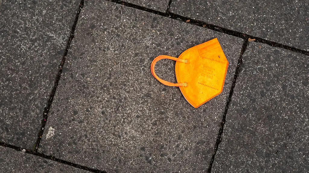 Ein-gebrauchter-orangefarbener-Mund-Nasen-Schutz-liegt-auf-dem-Gehweg