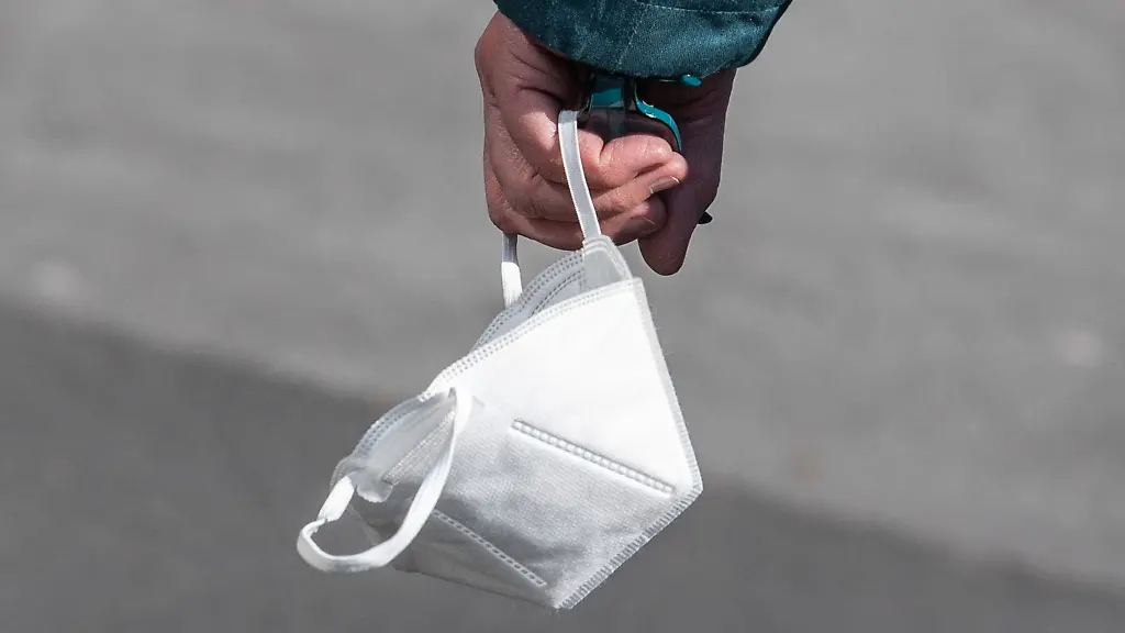 Ein-Passant-traegt-eine-FFP2-Maske-in-der-Hand