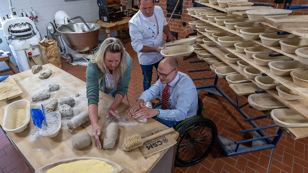 In-der-vogtlaendischen-Goldbroetchen-Baeckerei-bekommt-Maximilian-Eichinger-r-Inklusionsbeauftragter-der-Regionaldirektion-der-Bundesagentur-fuer-Arbeit-in-Sachsen-von-Baeckermeister-und-Inhaber-Gerd-Ralf-Jahnsmueller-und-Konditorin-Ariana-Strobel-einen-Einblick-in-den-Produktionsalltag-der-Baeckerei-vermittelt