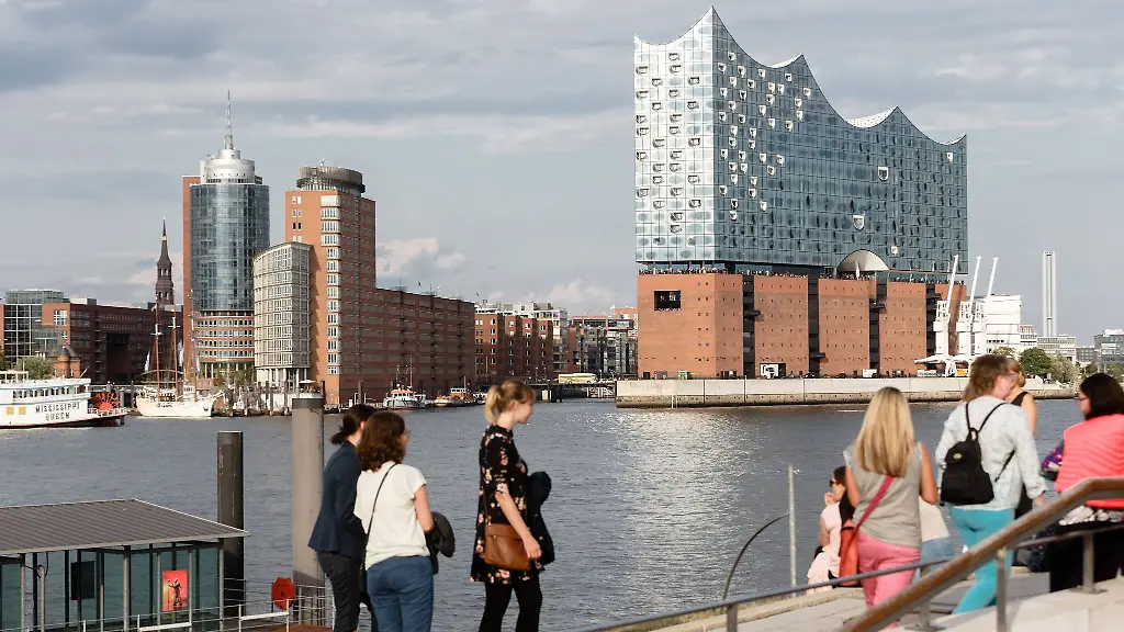 Touristinnen-stehen-am-suedlichen-Elbufer-am-Anleger-Koenig-der-Loewen-mit-Blick-auf-die-Elbphilharmonie