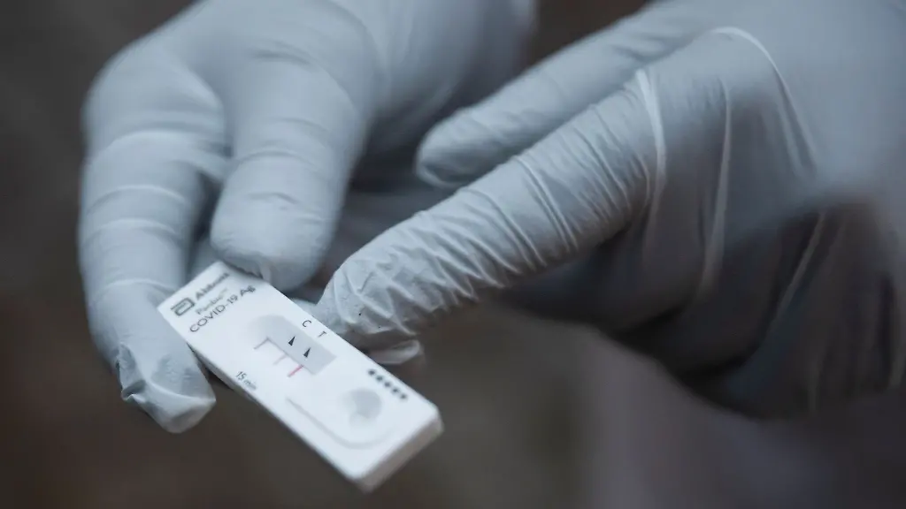 Ein-Mitarbeiter-des-Roten-Kreuzes-haelt-einen-Corona-Schnelltest-in-der-Hand