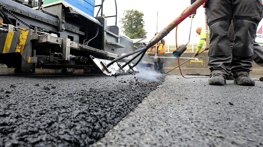 Arbeiter-tragen-auf-einer-Autobahn-eine-neue-Asphaltdecke-auf