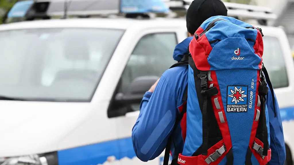 Ein-Mitglied-der-Bergwacht-steht-in-Ausruestung-vor-einem-Einsatzfahrzeug