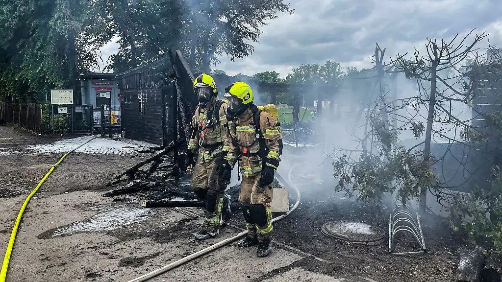 Einsatzkraefte-der-Feuerwehr-verlassen-unter-Atemschutz-das-Gelaende-eines-Sportvereins