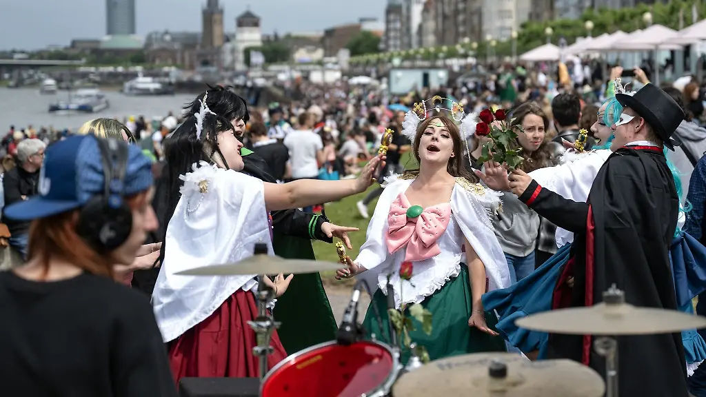 Verkleidete-Besucherinnen-und-Besucher-tanzen-am-Rheinufer-zu-Schlagzeugklaengen